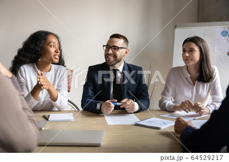 Smiling diverse businesspeople talk cooperate at briefing in office Smiling diverse businesspeople talk cooperate at briefing in office 64529217