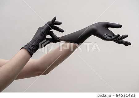 Hands in black silicone gloves on a light background. Hands in black silicone gloves on a light background. 64531433