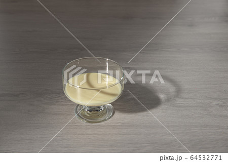 condensed milk in a transparent glass bowl on a wooden background condensed milk in a transparent glass bowl on a wooden background 64532771
