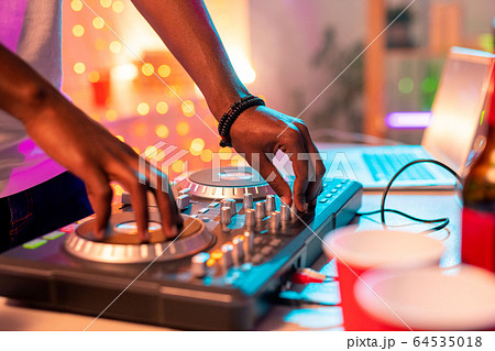 Hands of African guy moving turntable and turning switch while mixing sound 64535018