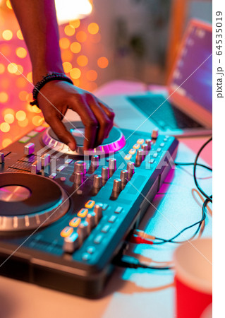 Hand of young deejay of African ethnicity over turntable going to add volume Hand of young deejay of African ethnicity over turntable going to add volume 64535019