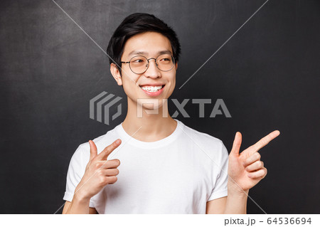 Close-up portrait of good-looking asian man in white t-shirt and glasses, spot friend on other side of room, pointing finger pistols at right side, smiling saying hi, informal greeting concept Close-up portrait of good-looking asian man in white t-shirt and glasses, spot friend on other side of room, pointing finger pistols at right side, smiling saying hi, informal greeting concept 64536694