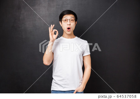 Amazed and enthusiastic young surprised asian guy left speechless and impressed after seeing premier of new movie, show okay sign look astounded standing black background Amazed and enthusiastic young surprised asian guy left speechless and impressed after seeing premier of new movie, show okay sign look astounded standing black background 64537058