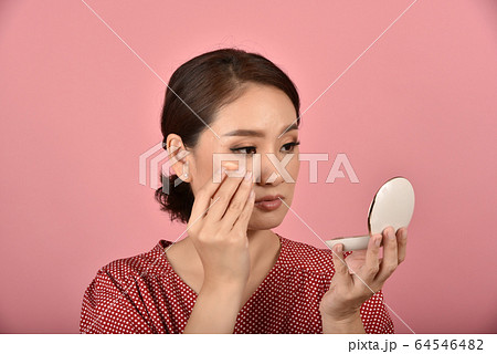 Asian woman looking at her facial problem in the mirror. Asian woman looking at her facial problem in the mirror. 64546482