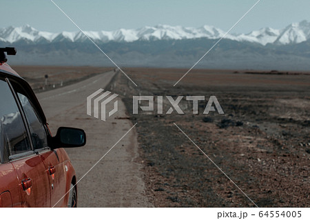Open road to mountain with car in the left of the frame 64554005