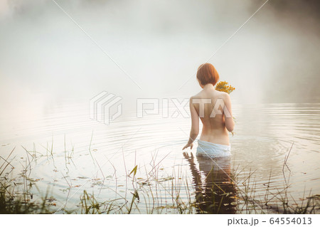 Half-naked attractive woman standing in misty lake 64554013