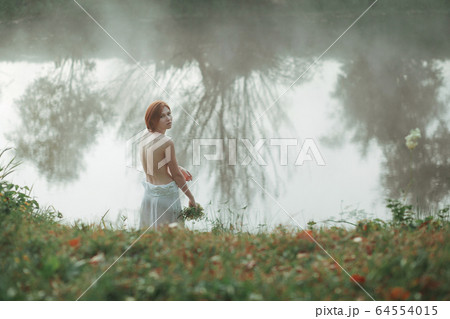 Beautiful young woman standing by the lake 64554015