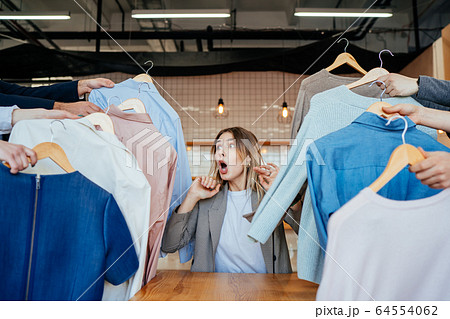 Young stylist looking through set of shirts for fashion shooting Young stylist looking through set of shirts for fashion shooting 64554062