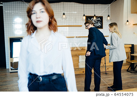 Two coworkers Staring and Gossiping About Their Female Colleague Two coworkers Staring and Gossiping About Their Female Colleague 64554075