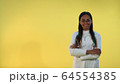 Black female doctor in lab coat smiling to the camera on yellow background. 64554385