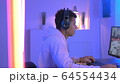 Medium shot of young black gammer in headphones playing in online shooter 64554434