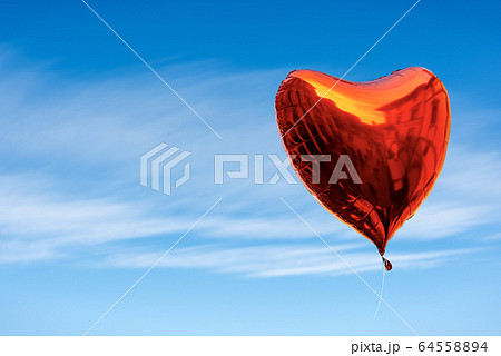 Red balloon in the shape of a heart in a blue sky with clouds Red balloon in the shape of a heart in a blue sky with clouds 64558894