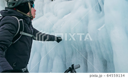 Man is riding bicycle near ice grotto. Rock with ice caves icicl 64559134