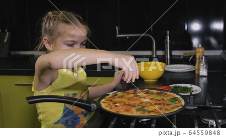 Smart girl learning to cook. Young mistress children to cook a Neapolitan egg fried omelette from salame affumicato sausage. Smart girl learning to cook. Young mistress children to cook a Neapolitan egg fried omelette from salame affumicato sausage. 64559848