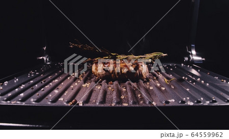 Delicious juicy meat steak cooking on grill. Prime beef fry on electric roaster, rosemary, black pepper, salt. Slow motion. 64559962