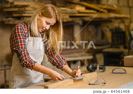 beautiful carpenter woman making marks on wooden piece beautiful carpenter woman making marks on wooden piece 64561408