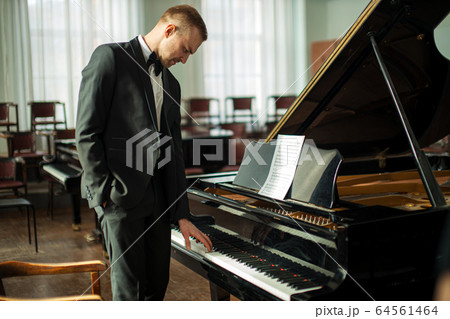 young caucasian man stand next to piano 64561464