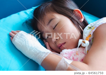Close up of illness asian child admitted in hospital with saline intravenous (IV) on hand. 64561750