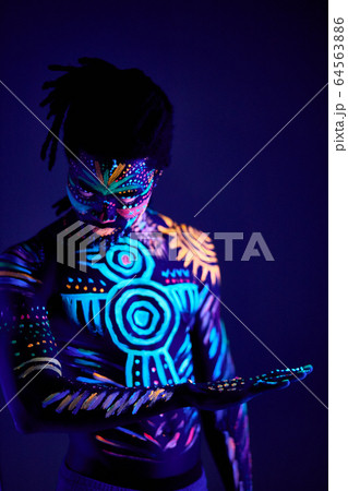 african man painted in fluorescent paint on face and muscular torso 64563886