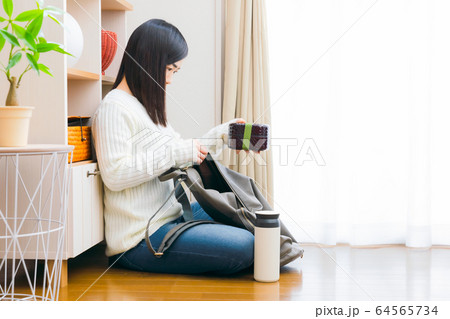 弁当箱と水筒をリュックに入れる女性 64565734