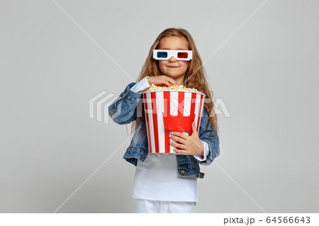 child girl wearing red-blue 3d glasses having fun and holding popcorn bucket child girl wearing red-blue 3d glasses having fun and holding popcorn bucket 64566643