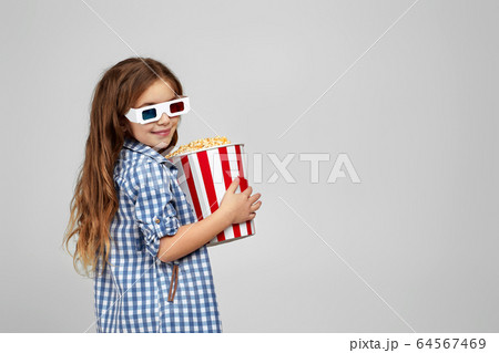 child girl wearing red-blue 3d glasses and eating popcorn 64567469