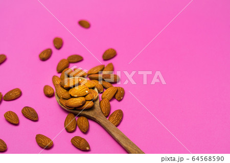 Almonds on a wooden spoon 64568590