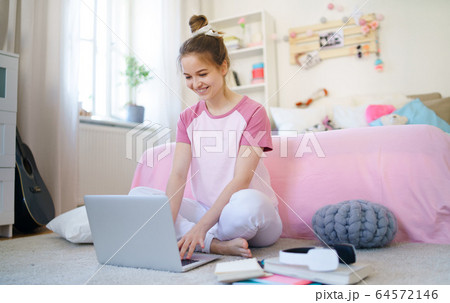 Young girl with laptop sitting on floor, relaxing during quarantine. Young girl with laptop sitting on floor, relaxing during quarantine. 64572146