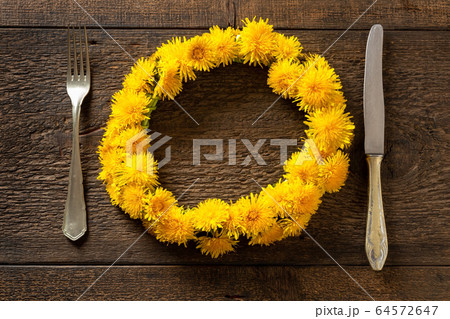 Dandelion wreath on a table with a fork and knife 64572647