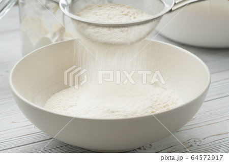 Flour sifting through a sieve for a baking 64572917