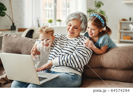 Happy aged woman with grandchildren using laptop 64574294
