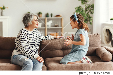 Girl speaking and sharing secret with grandmother. 64574296