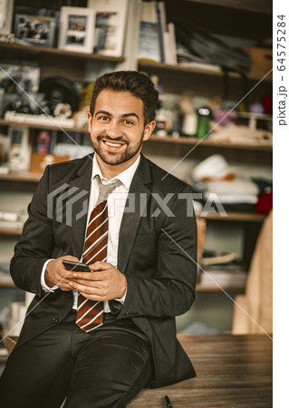 Handsome Business Man Sits On Table Chatting By Phone Handsome Business Man Sits On Table Chatting By Phone 64575284
