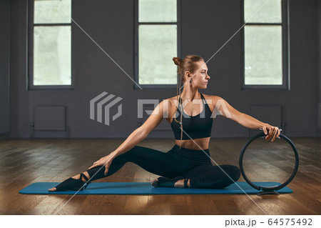 The girl is training her hands with a fitness expander in the gym, doing push-ups, training the upper body, shoulders, chest, triceps. Fitness motivation, copy space. 64575492