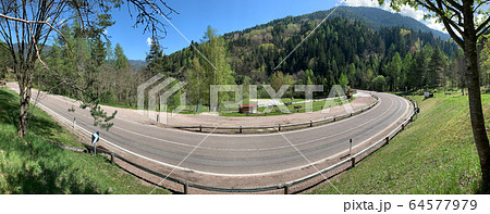 Italy, twisted road of the Alps mountains, without cars, a picturesque view of mountains, sunny weather, Zone for picnic, benches for rest Italy, twisted road of the Alps mountains, without cars, a picturesque view of mountains, sunny weather, Zone for picnic, benches for rest 64577979