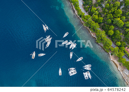 Aerial view of a much chaotically standing boats in a bay at sunset, Croatia, coastline with azure water and green trees, Transparent water, reef under water 64578242