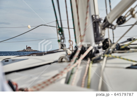 Croatia, Adriatic Sea, 19 September 2019: The race of sailboats, a lot of ropes, bright colors, view of lighthouse through ropes and mast 64579787