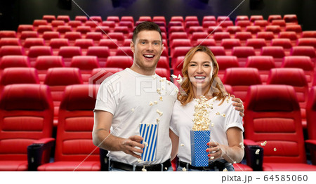happy couple in t-shirts with popcorn at cinema happy couple in t-shirts with popcorn at cinema 64585060
