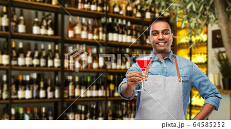 indian barman with glass of cocktail at bar 64585252