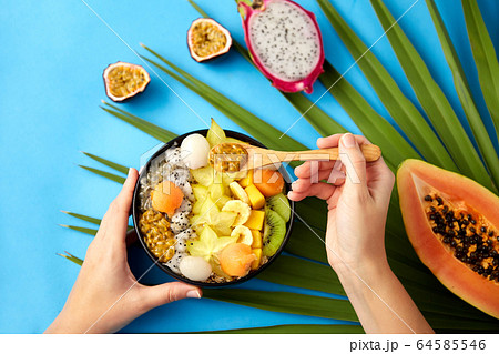 hands with mix of exotic fruits and wooden spoon hands with mix of exotic fruits and wooden spoon 64585546