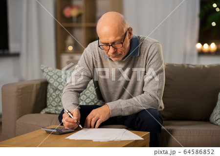 senior man with bills and calculator at home 64586852