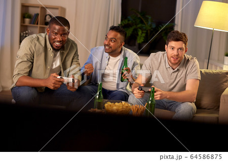 happy friends playing video games at home at night 64586875