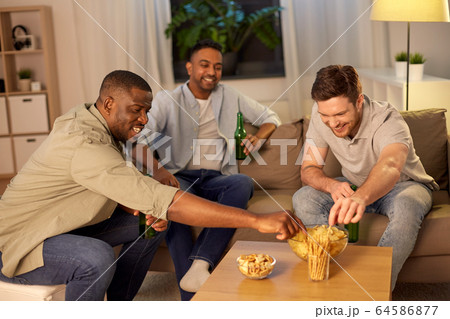 male friends drinking beer with crisps at home 64586877