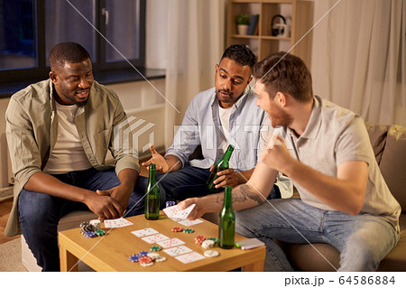 smiling male friends playing cards at home smiling male friends playing cards at home 64586884