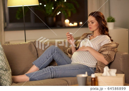 sick pregnant woman with thermometer at home sick pregnant woman with thermometer at home 64586899