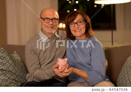 happy senior couple with piggy bank at home happy senior couple with piggy bank at home 64587036