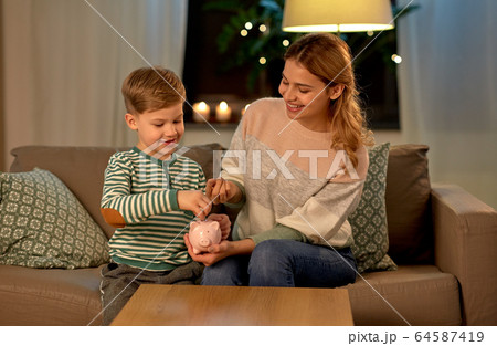 mother and little son with piggy bank at home mother and little son with piggy bank at home 64587419