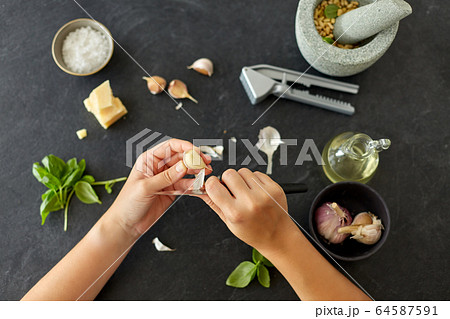 hands peeling garlic with knife for pesto sauce hands peeling garlic with knife for pesto sauce 64587591
