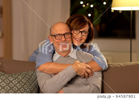 happy senior couple hugging on sofa at home happy senior couple hugging on sofa at home 64587901