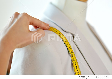 fashion designer measures jacket with tape measure 64588230